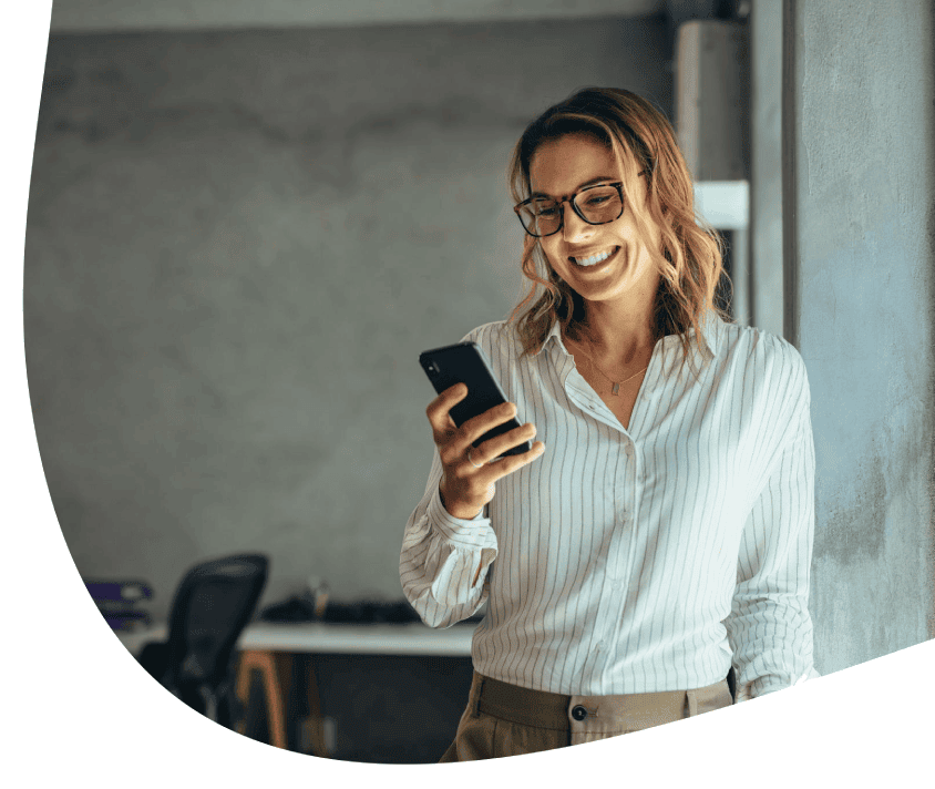 Stojąca kobieta z uśmiechem wpatrzona w telefon w białej ramce