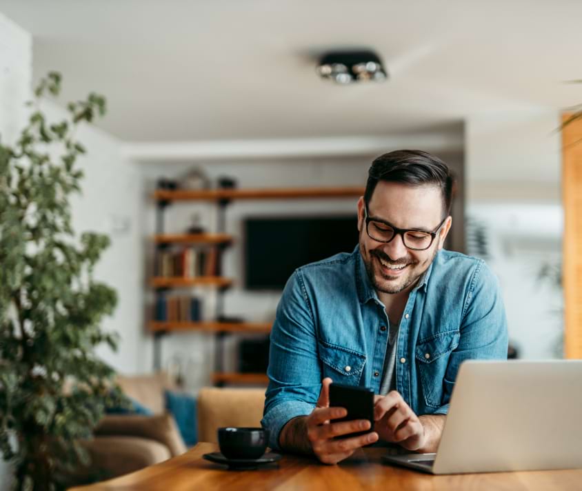Mężczyzna przy biurku wpatrzony w telefon Mężczyzna przy biurku wpatrzony w telefon
